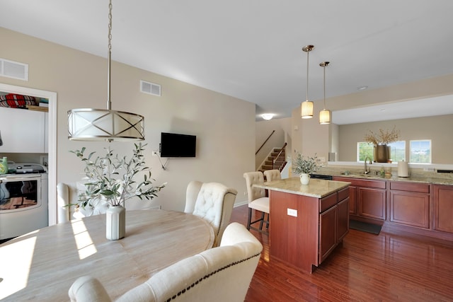 dining area featuring dark wood-type flooring, washer / dryer, and sink