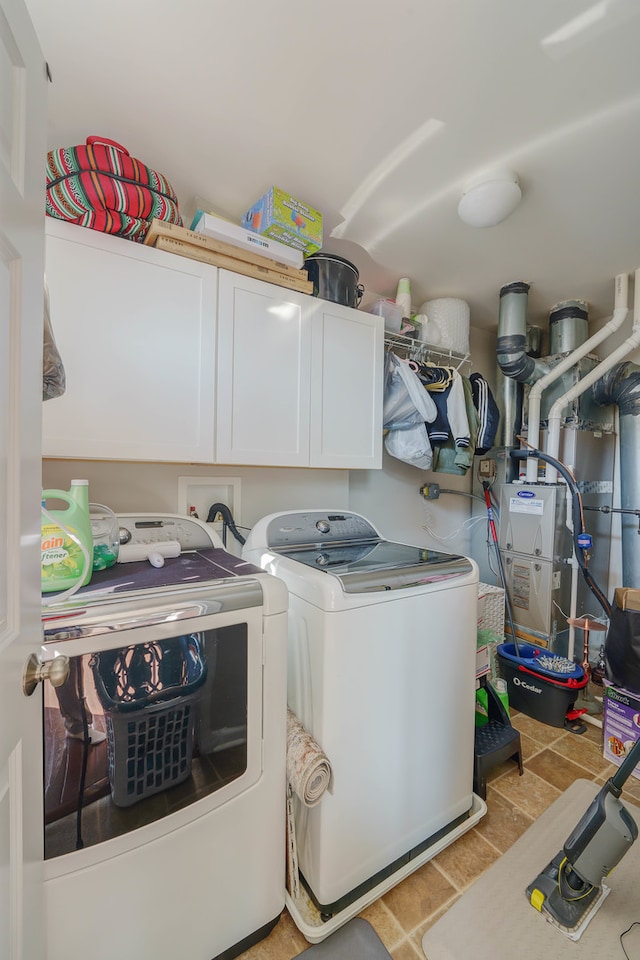 clothes washing area with cabinets and washing machine and dryer