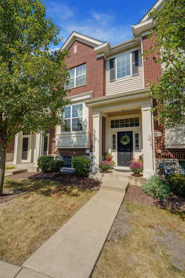 townhome / multi-family property with a front lawn and covered porch