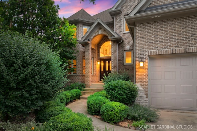 exterior entry at dusk featuring a garage