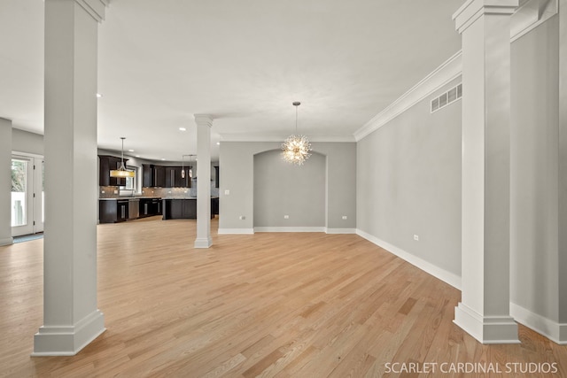 unfurnished living room with decorative columns, crown molding, a chandelier, and light hardwood / wood-style flooring