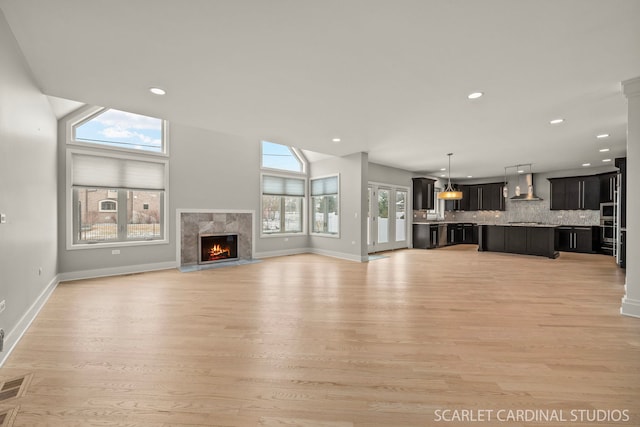 unfurnished living room featuring a high end fireplace and light hardwood / wood-style floors