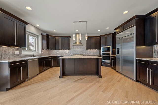 kitchen featuring pendant lighting, light hardwood / wood-style flooring, a center island, extractor fan, and stainless steel gas cooktop