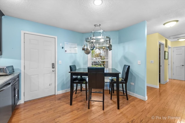 dining room with light hardwood / wood-style floors and a textured ceiling