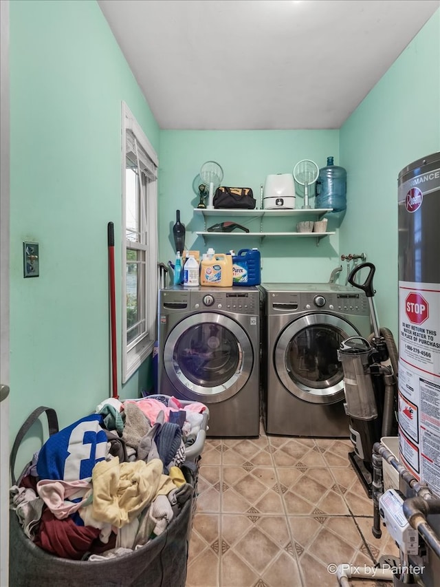 laundry room with light tile patterned floors, gas water heater, and washer and dryer