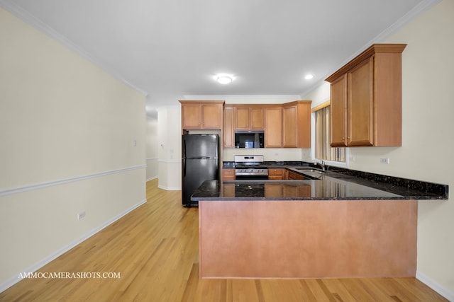 kitchen featuring dark stone counters, black appliances, ornamental molding, and kitchen peninsula