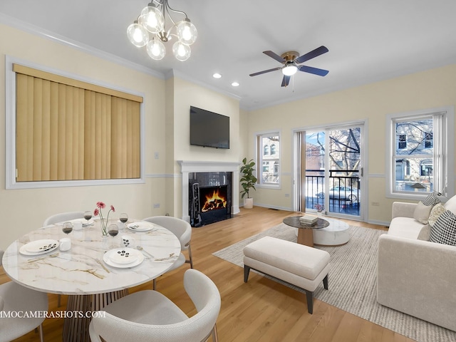 living room with ceiling fan with notable chandelier, light wood-type flooring, and crown molding