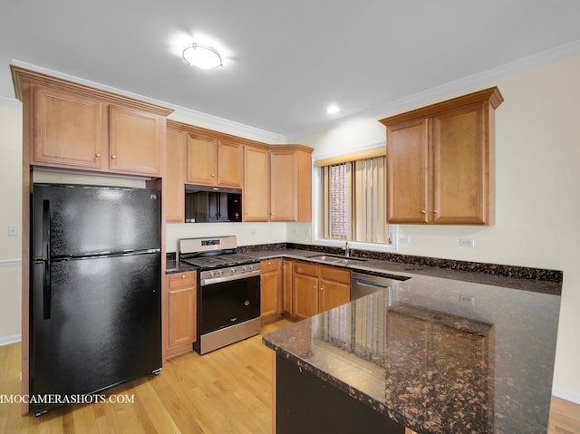 kitchen with ornamental molding, stainless steel appliances, dark stone counters, and light hardwood / wood-style flooring