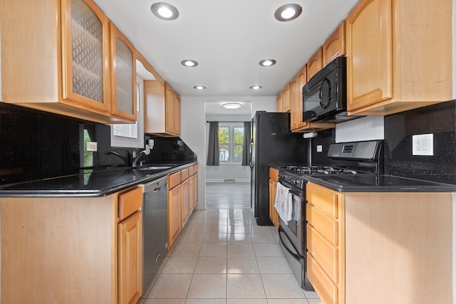 kitchen with decorative backsplash, light brown cabinets, dark stone counters, black appliances, and light tile patterned flooring