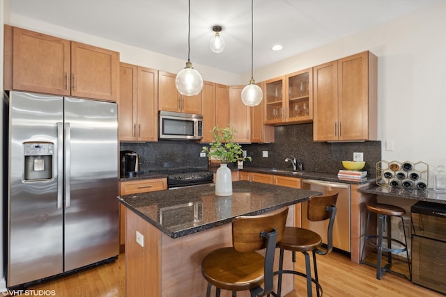 kitchen featuring a breakfast bar, appliances with stainless steel finishes, decorative backsplash, and decorative light fixtures