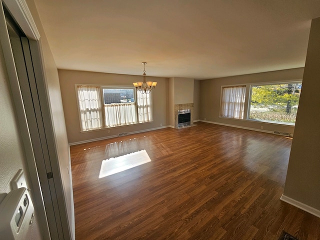 unfurnished living room featuring dark hardwood / wood-style floors, a chandelier, and a wealth of natural light