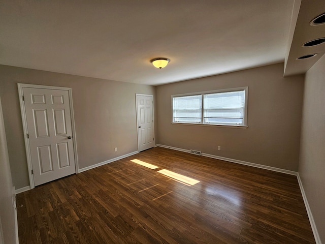 unfurnished room with dark wood-type flooring