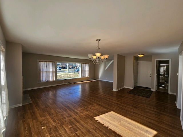 spare room with an inviting chandelier and dark hardwood / wood-style flooring