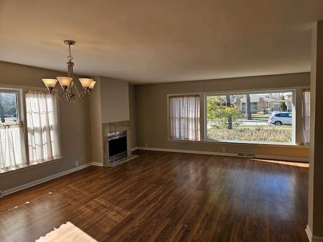 unfurnished living room with a fireplace, dark wood-type flooring, and a chandelier