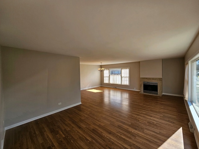 unfurnished living room with an inviting chandelier and dark hardwood / wood-style floors