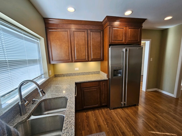 kitchen with light stone counters, dark hardwood / wood-style floors, stainless steel fridge with ice dispenser, and sink