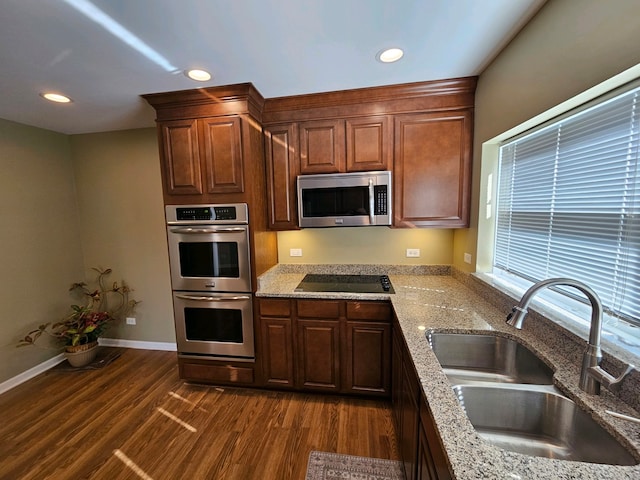 kitchen featuring appliances with stainless steel finishes, sink, dark wood-type flooring, and light stone counters