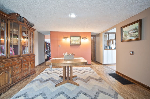 dining area with a textured ceiling and light hardwood / wood-style flooring