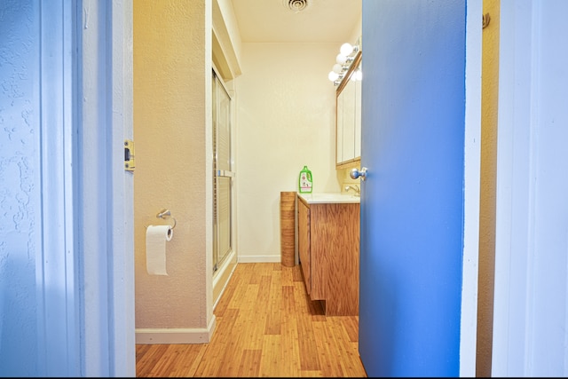 bathroom featuring vanity, hardwood / wood-style flooring, and a shower with shower door