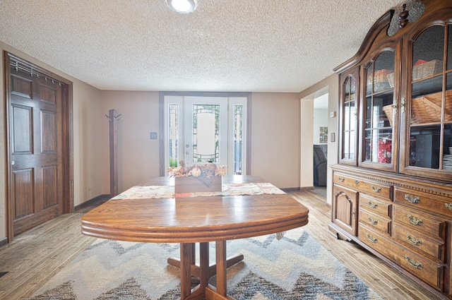 dining room with light wood-type flooring and a textured ceiling