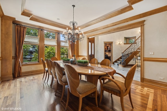 dining area with a raised ceiling, a chandelier, hardwood / wood-style floors, and crown molding