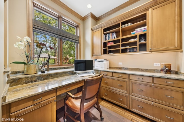 office area featuring ornamental molding, built in desk, and light hardwood / wood-style floors