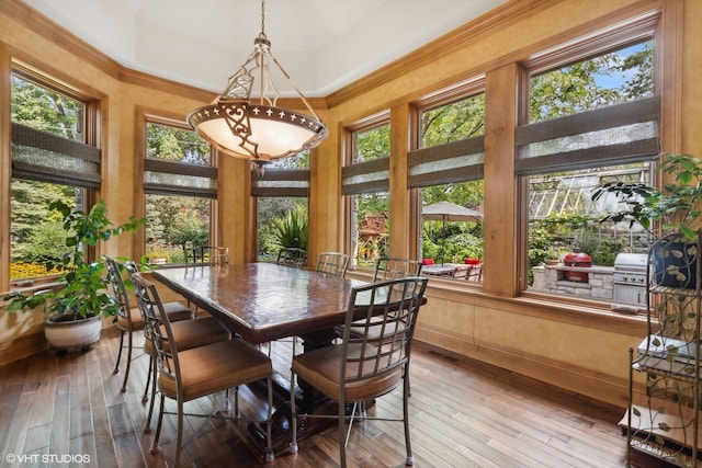 dining space with hardwood / wood-style floors, a healthy amount of sunlight, and crown molding