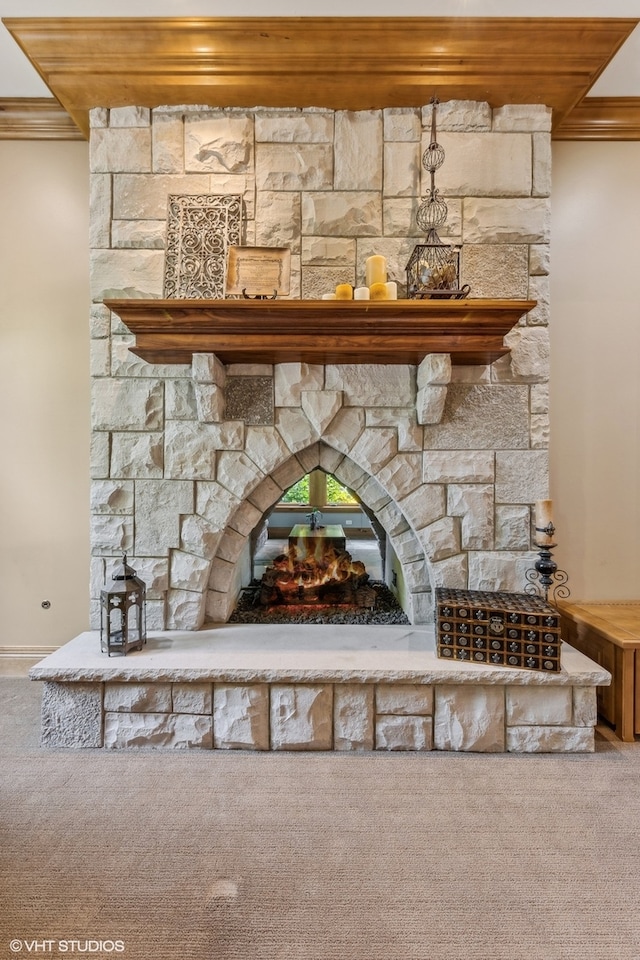 details with carpet, a stone fireplace, and ornamental molding