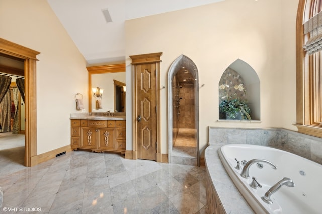 bathroom featuring lofted ceiling, vanity, and tiled bath