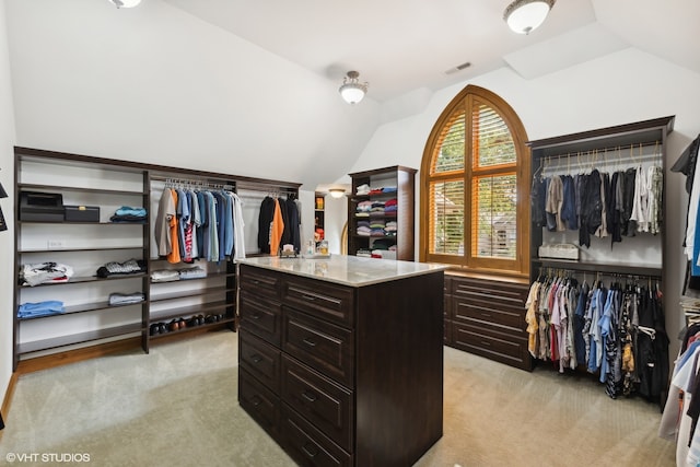 spacious closet with lofted ceiling and light colored carpet