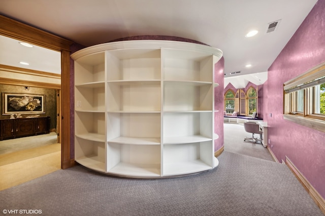 hallway with built in shelves and light colored carpet