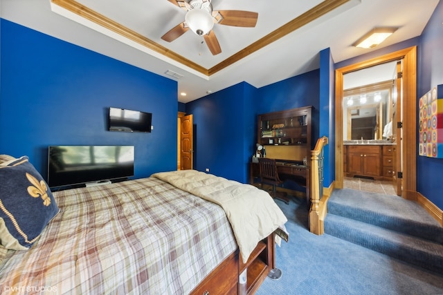 bedroom featuring a raised ceiling, crown molding, ceiling fan, ensuite bathroom, and light colored carpet