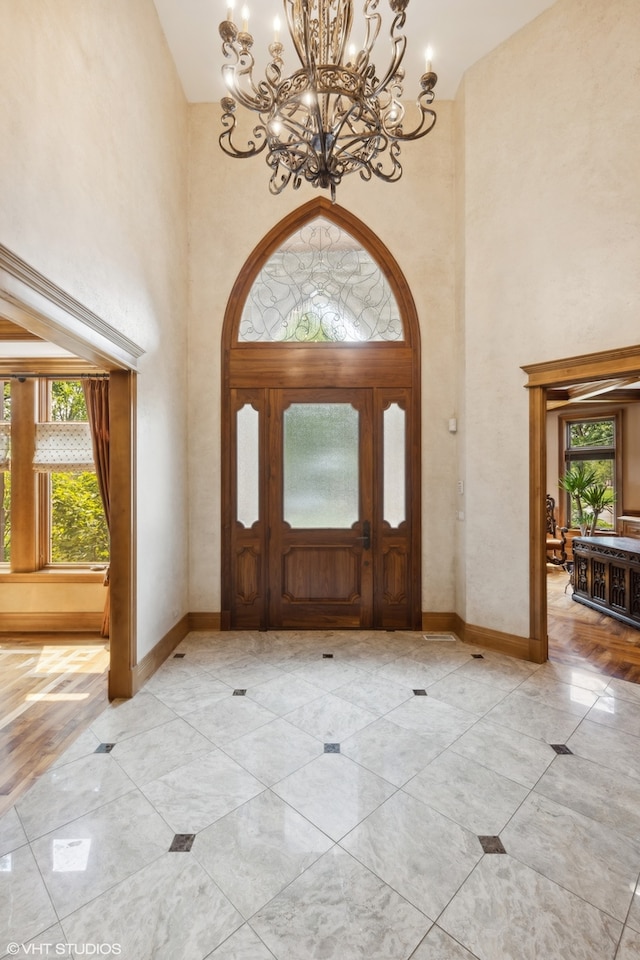 foyer entrance with light hardwood / wood-style flooring, a high ceiling, and a chandelier