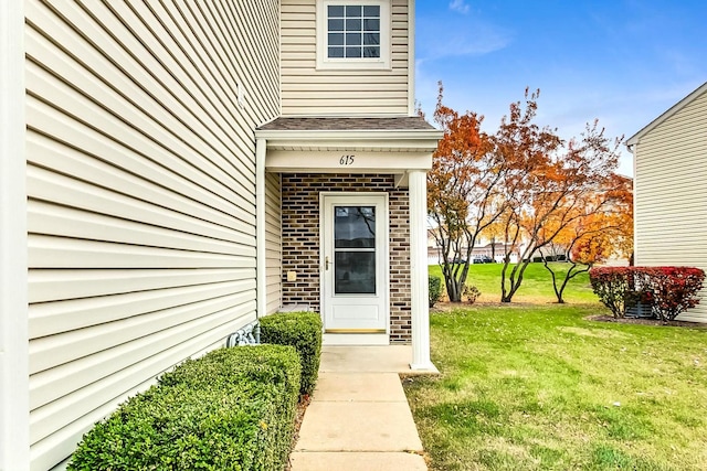 view of exterior entry featuring a lawn