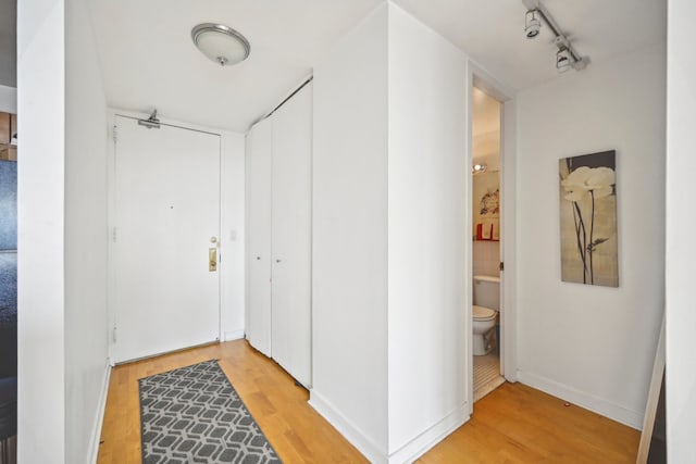 hall with track lighting and light hardwood / wood-style floors