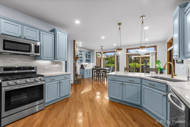 kitchen featuring appliances with stainless steel finishes, light hardwood / wood-style floors, sink, and blue cabinetry