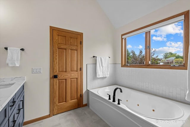 bathroom with tile patterned floors, vaulted ceiling, vanity, and a bathing tub