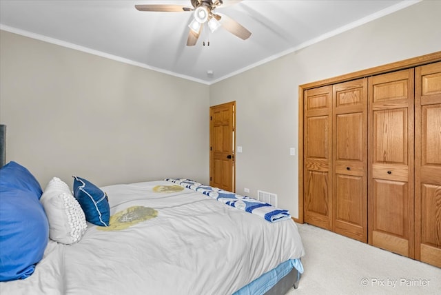 bedroom with ornamental molding, a closet, ceiling fan, and carpet floors