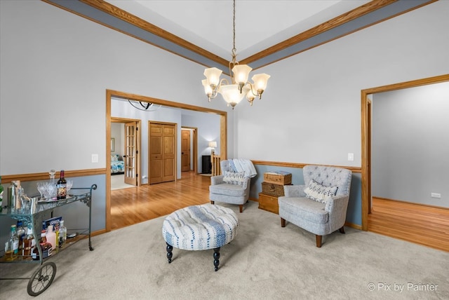 living area featuring wood-type flooring, a chandelier, and ornamental molding