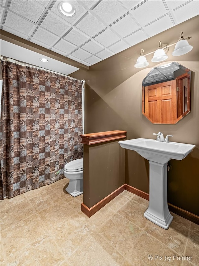 bathroom featuring a drop ceiling and toilet