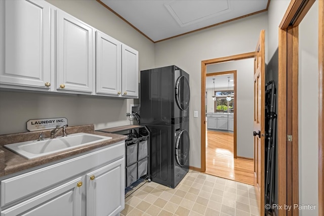 clothes washing area featuring cabinets, stacked washer / dryer, sink, and crown molding