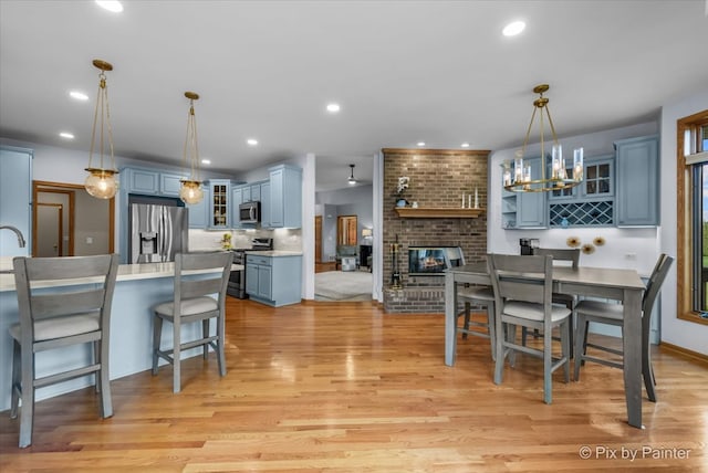 dining area featuring a chandelier, light hardwood / wood-style flooring, and a brick fireplace