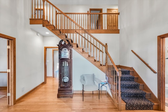 staircase with hardwood / wood-style floors and a towering ceiling