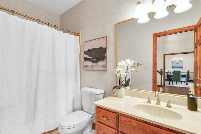 bathroom with an inviting chandelier, vanity, curtained shower, and toilet