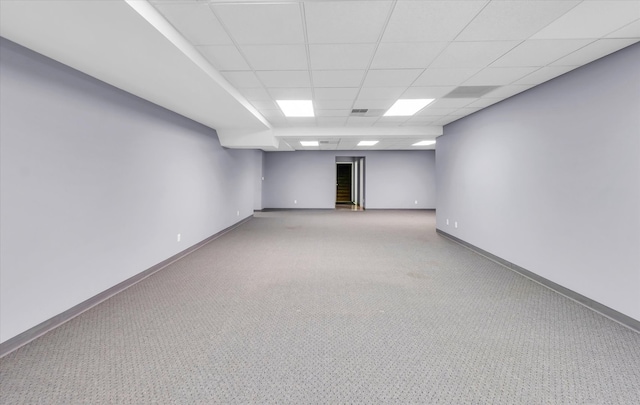 basement with a paneled ceiling and carpet flooring