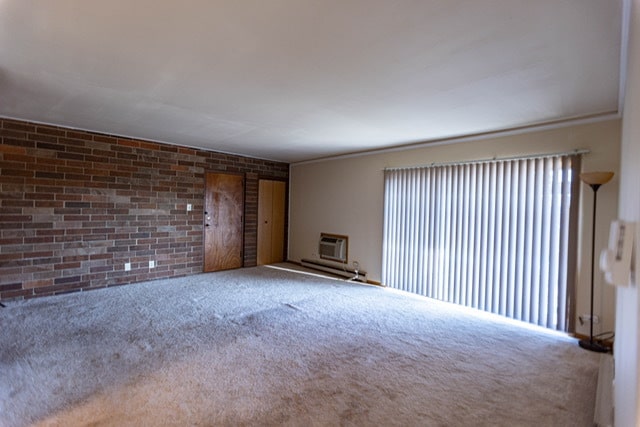 empty room featuring brick wall, carpet floors, and a wall mounted AC