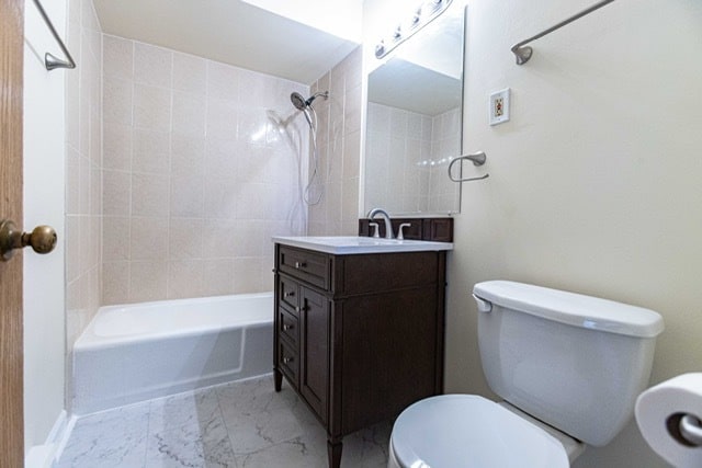 full bathroom with tiled shower / bath, vanity, and toilet