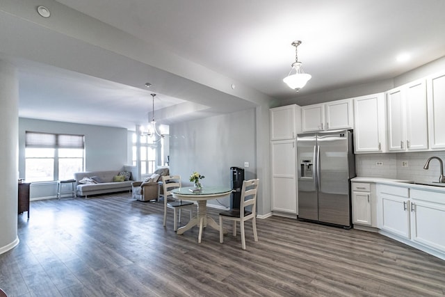 kitchen featuring decorative light fixtures, sink, white cabinets, stainless steel fridge, and dark wood-type flooring