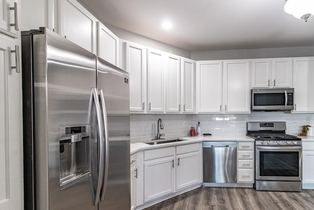 kitchen with appliances with stainless steel finishes, sink, hardwood / wood-style floors, and white cabinets