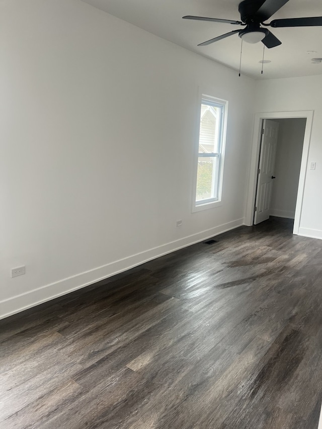 unfurnished room featuring baseboards, dark wood-style floors, visible vents, and ceiling fan